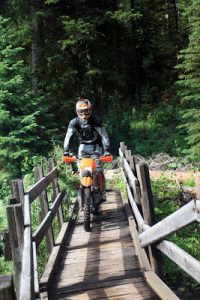 rider motorcycle crossing wood bridge